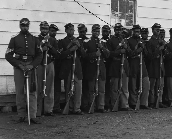Photograph of Washington, 1862-1865, view of the defenses of Washington. Shows 27 African Americans in two lines with rifles resting on the ground.