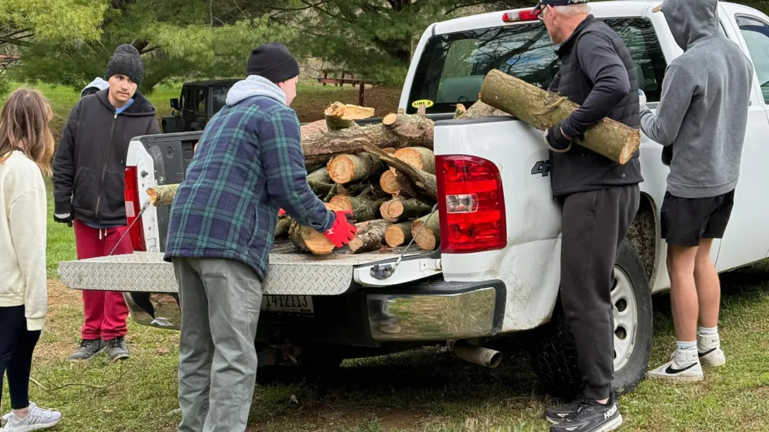 Volunteers unload wood from a white pickup truck